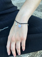 woman in black wearing a black cord bracelet with blue stone charm and pearl charm