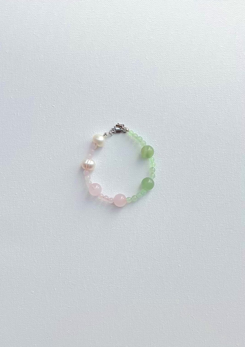 Beaded bracelet with pearls and green pink  stones on a white background