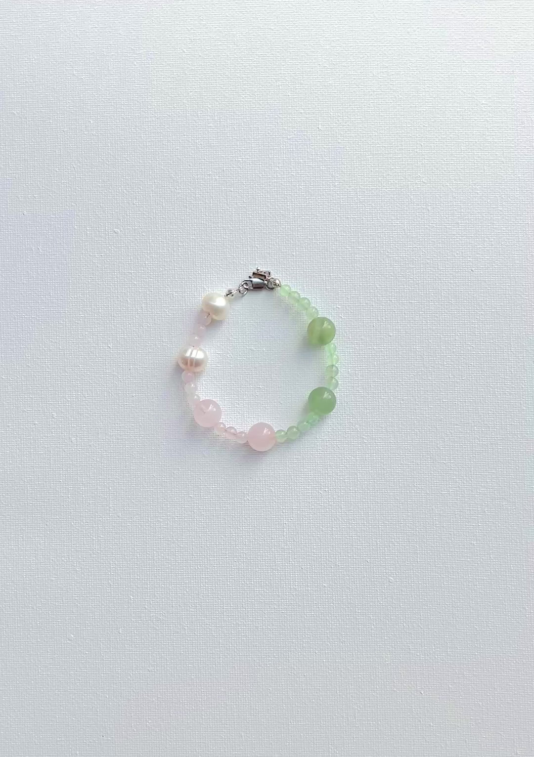 Beaded bracelet with pearls and green pink  stones on a white background
