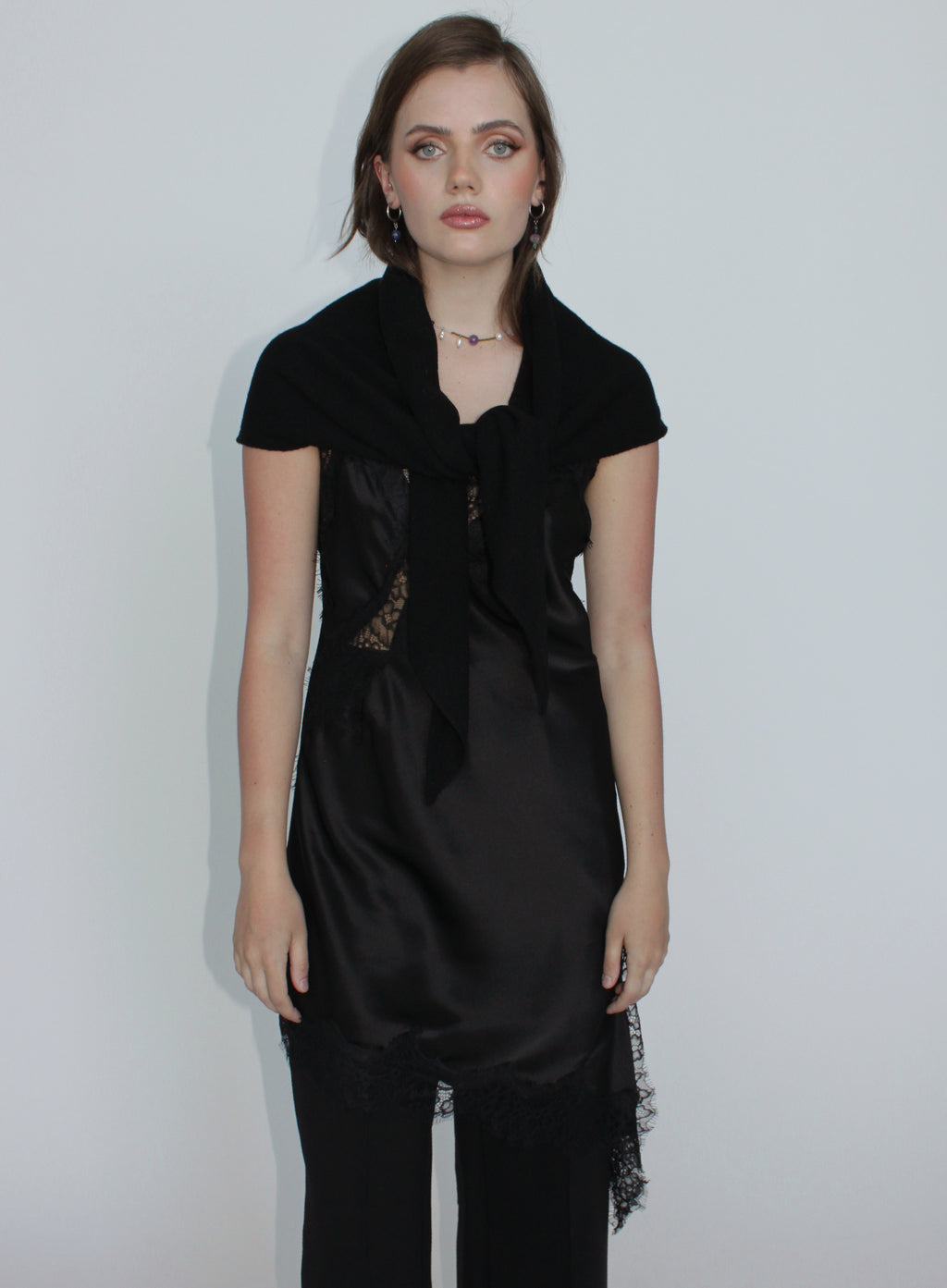 Woman wearing a black dress with lace details on a plain background