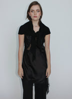 Woman wearing a black dress with lace details on a plain background