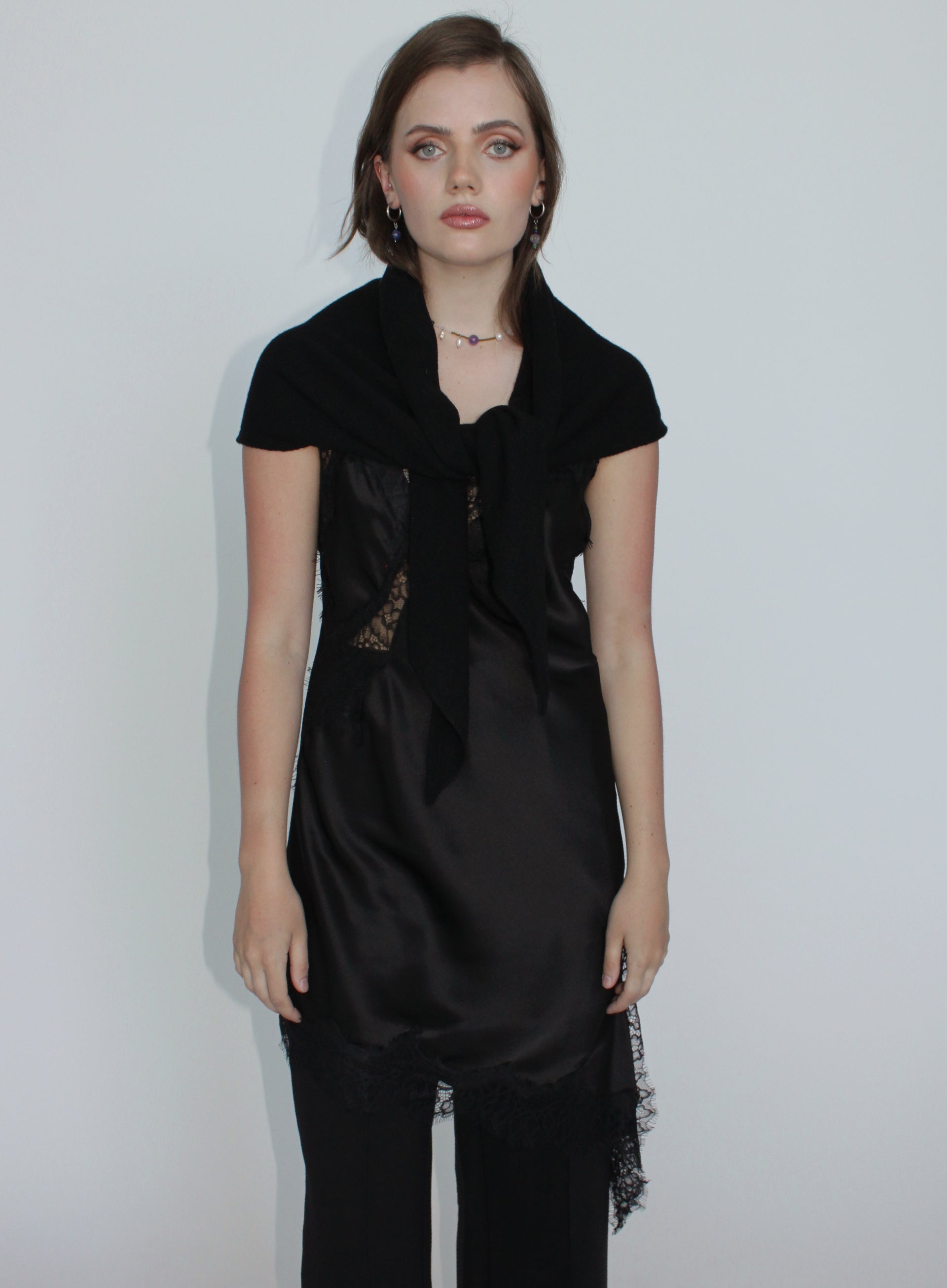 Woman wearing a black dress with lace details on a plain background