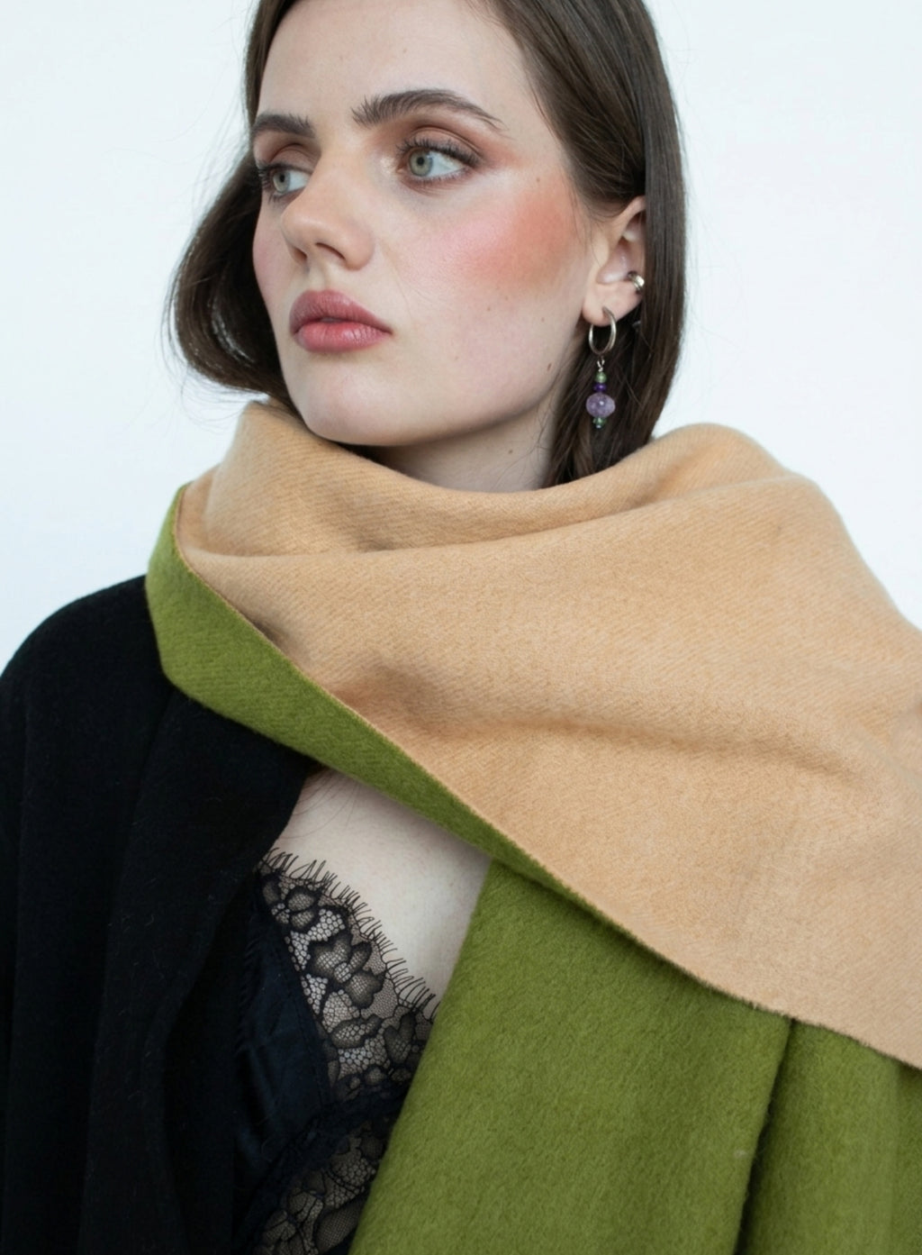 Woman wearing a green and beige scarf against a white background