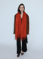 Woman wearing an orange scarf and brown coat on a white background
