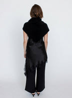 Person wearing a black outfit with a draped top and wide-leg pants on a white background
