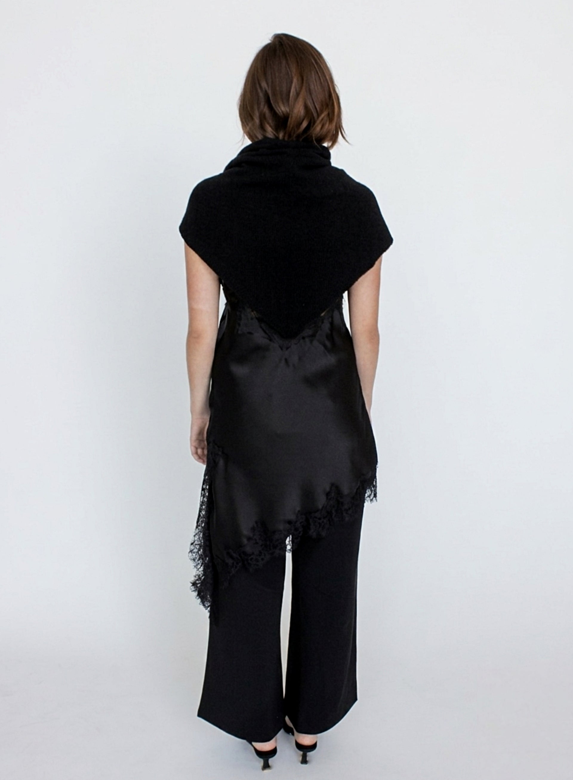 Person wearing a black outfit with a draped top and wide-leg pants on a white background