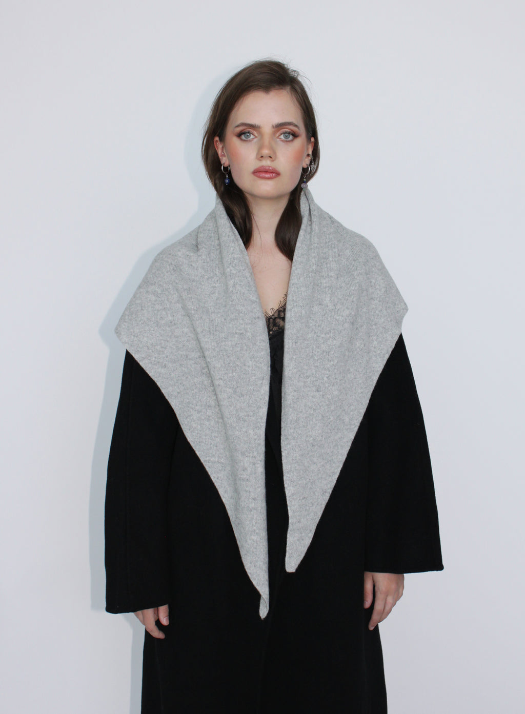 Woman wearing a black coat with a gray scarf against a white background