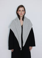 Woman wearing a black coat with a gray scarf against a white background