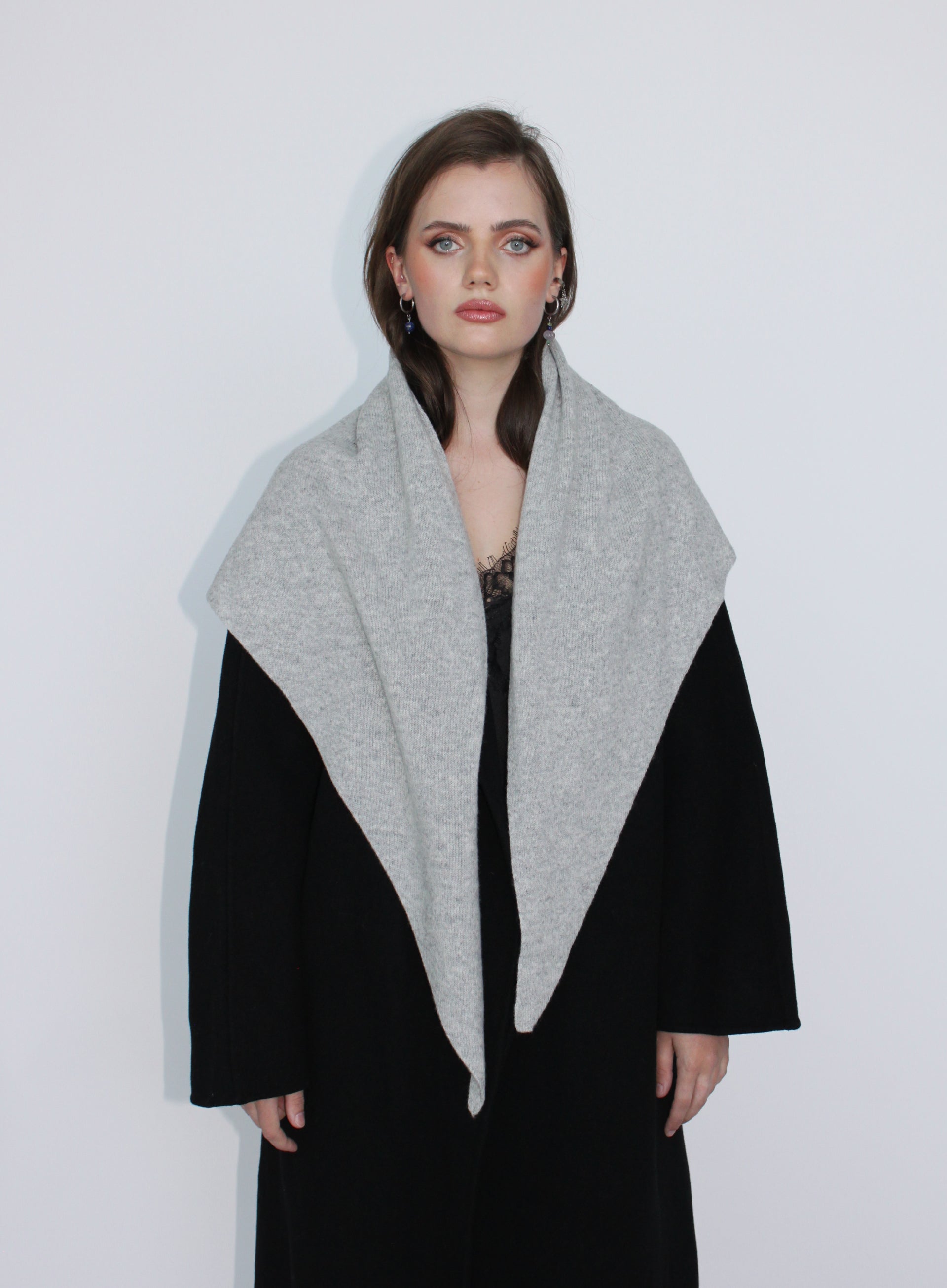 Woman wearing a black coat with a gray scarf against a white background