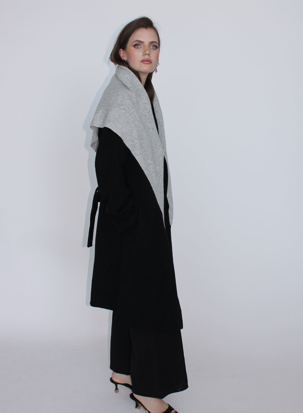 Woman wearing a black and gray coat against a white background