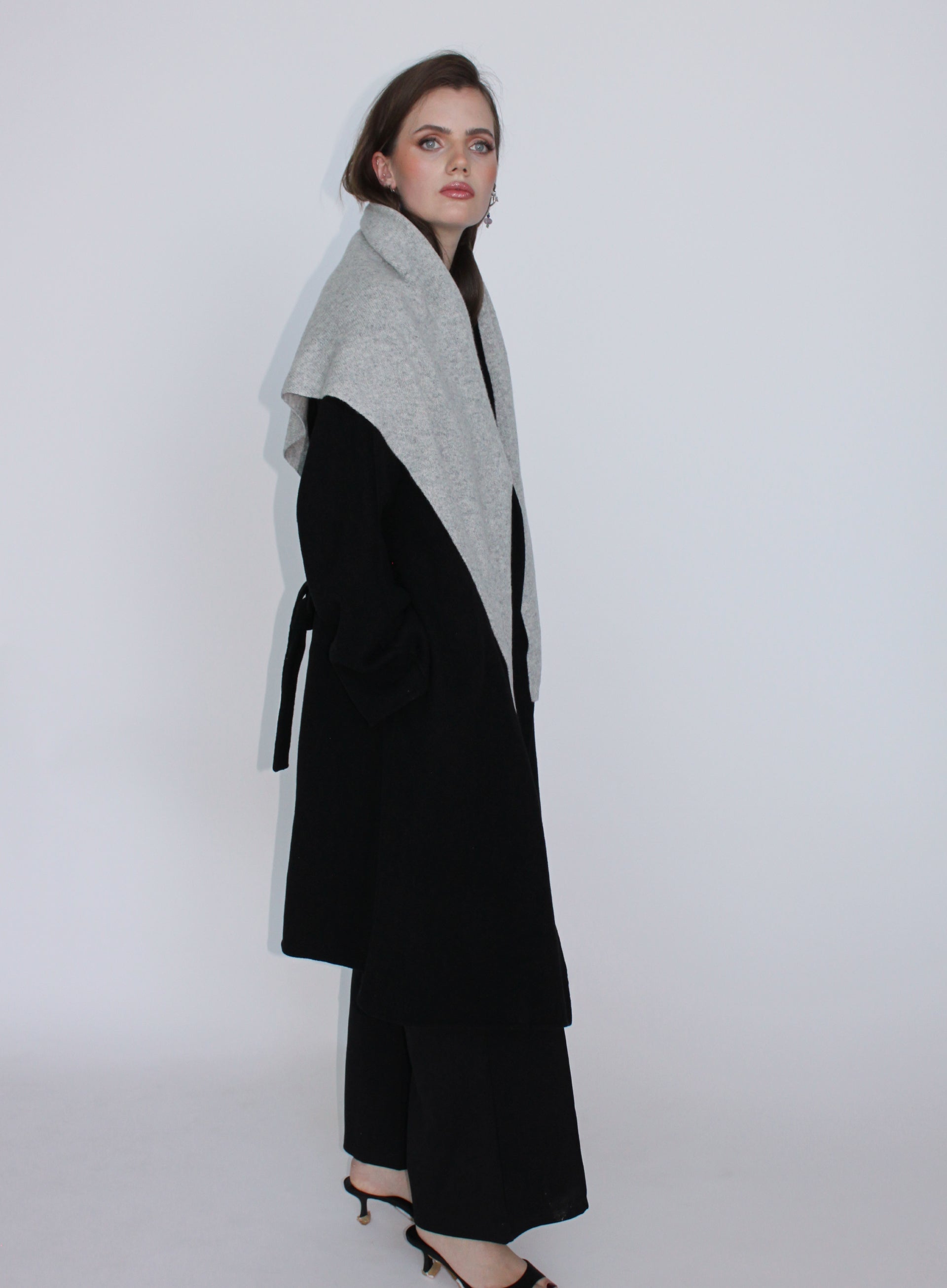 Woman wearing a black and gray coat against a white background