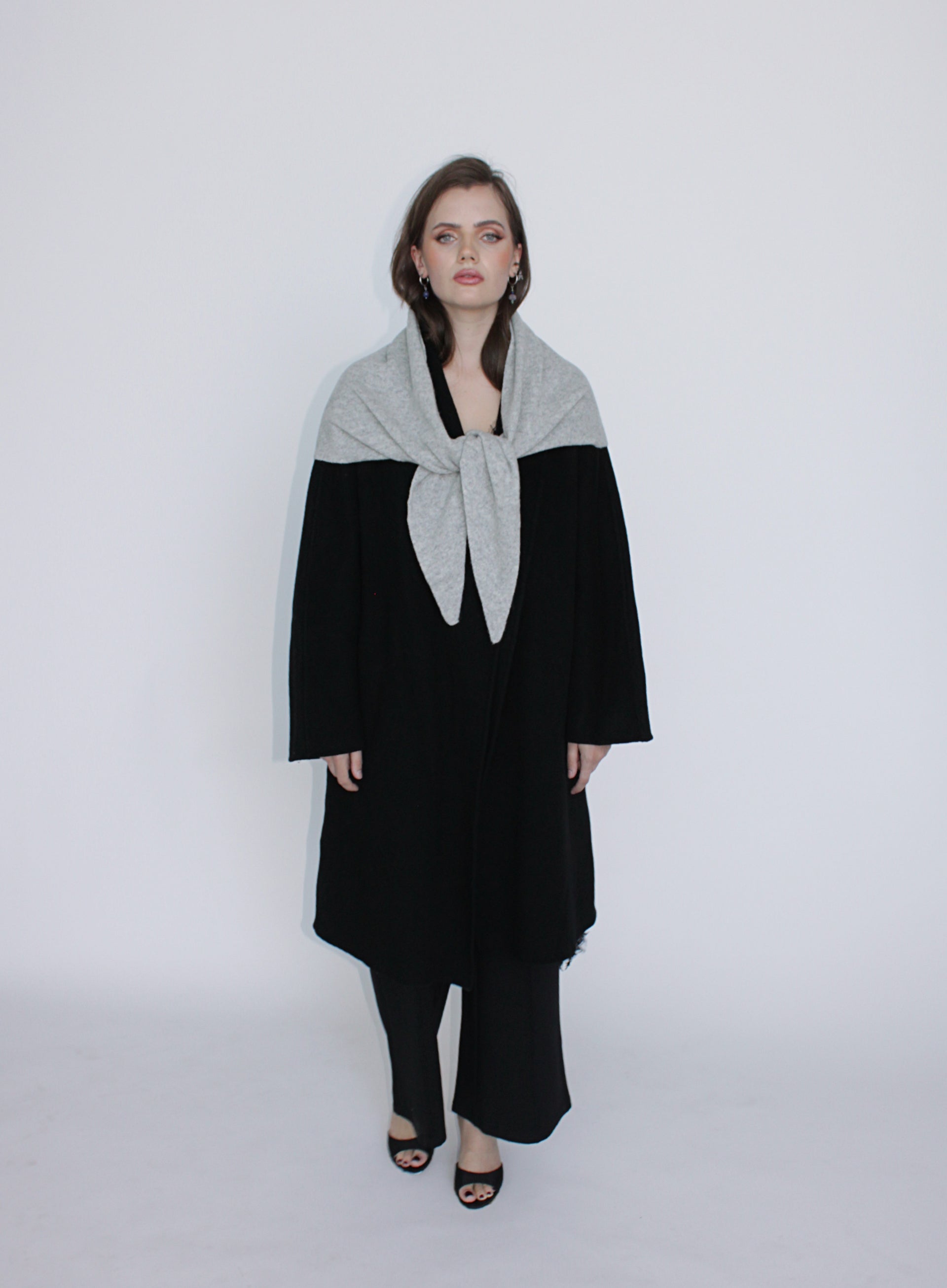 Woman wearing a black and gray outfit with a scarf on a white background