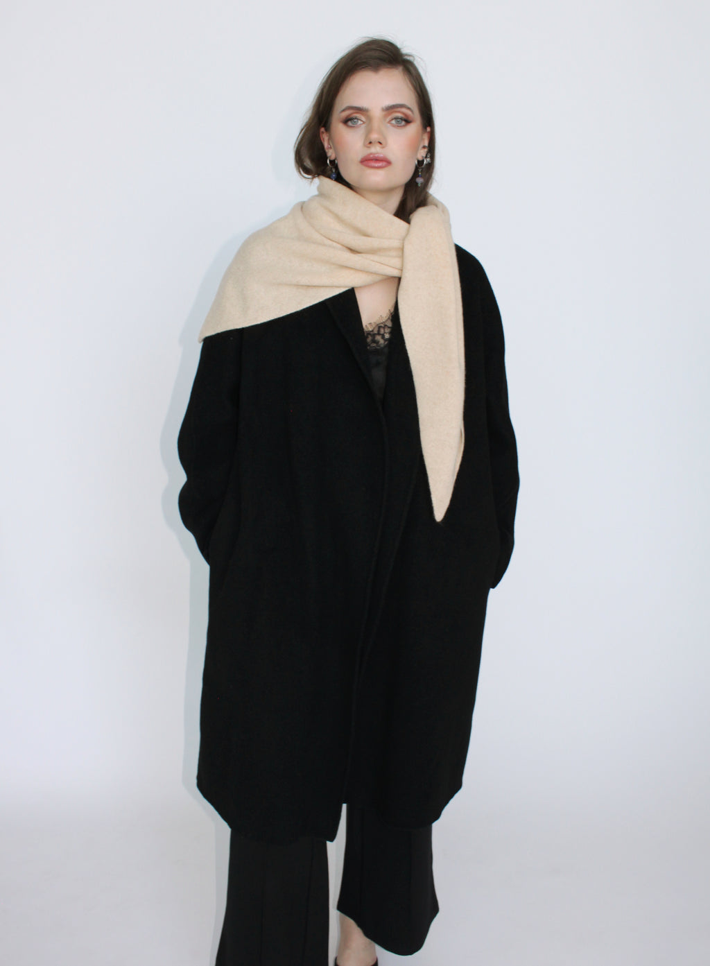 Woman wearing a black coat and beige scarf on a white background