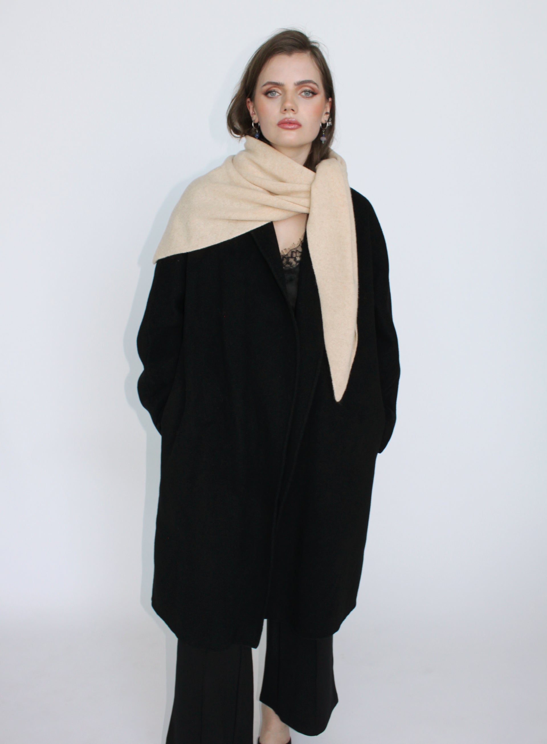 Woman wearing a black coat and beige scarf on a white background