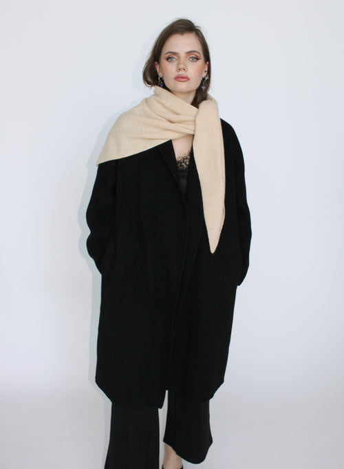 Woman wearing a black coat and beige scarf on a white background