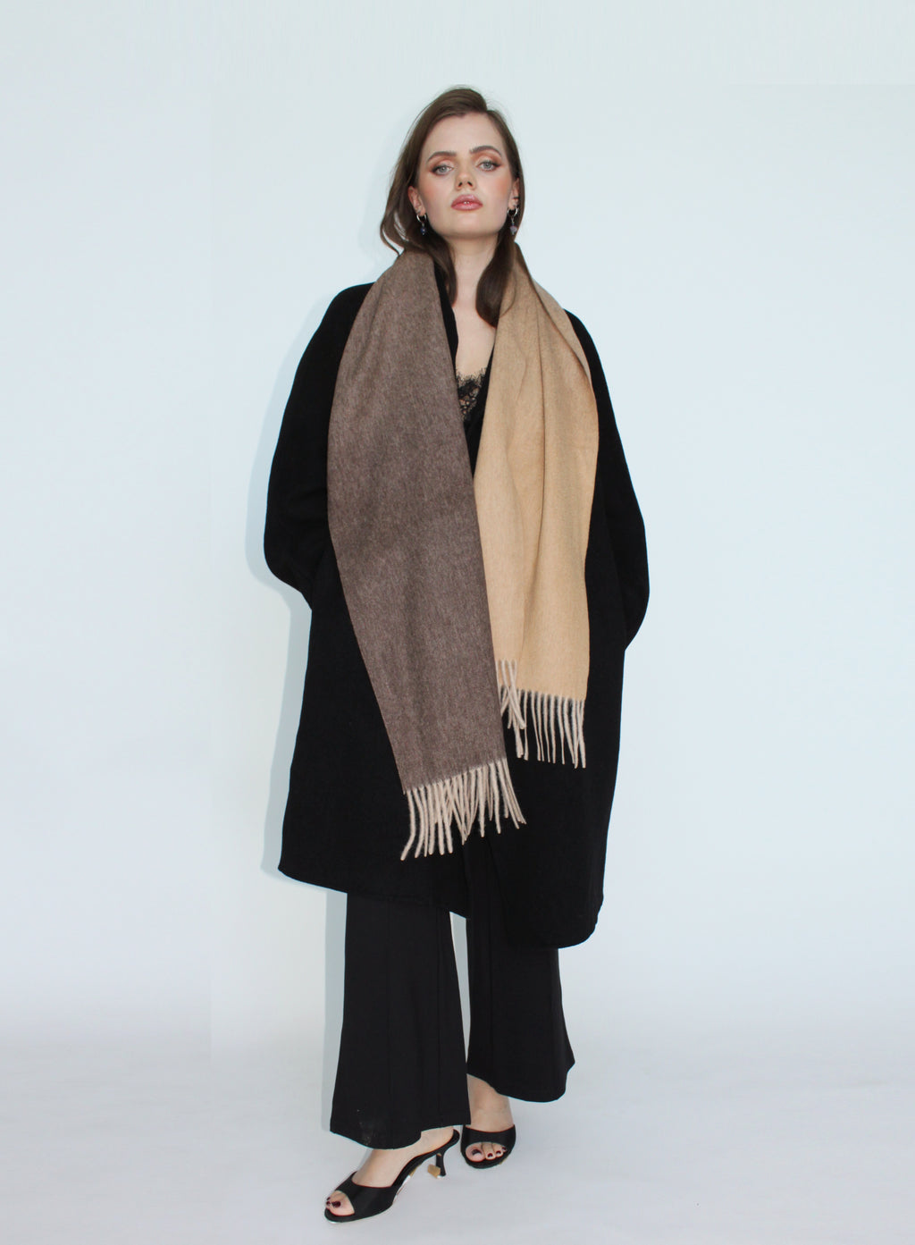 Woman wearing a black coat and two-tone scarf on a white background