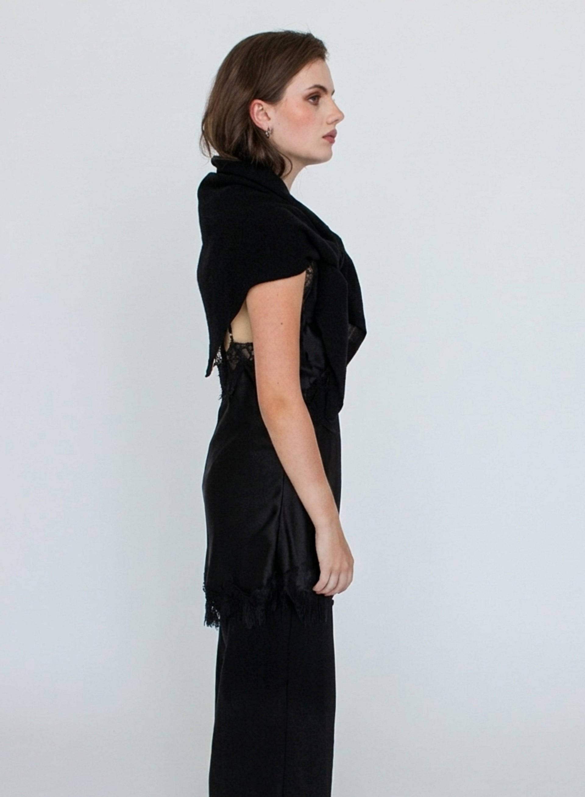 Woman wearing a black shawl over a black dress against a white background