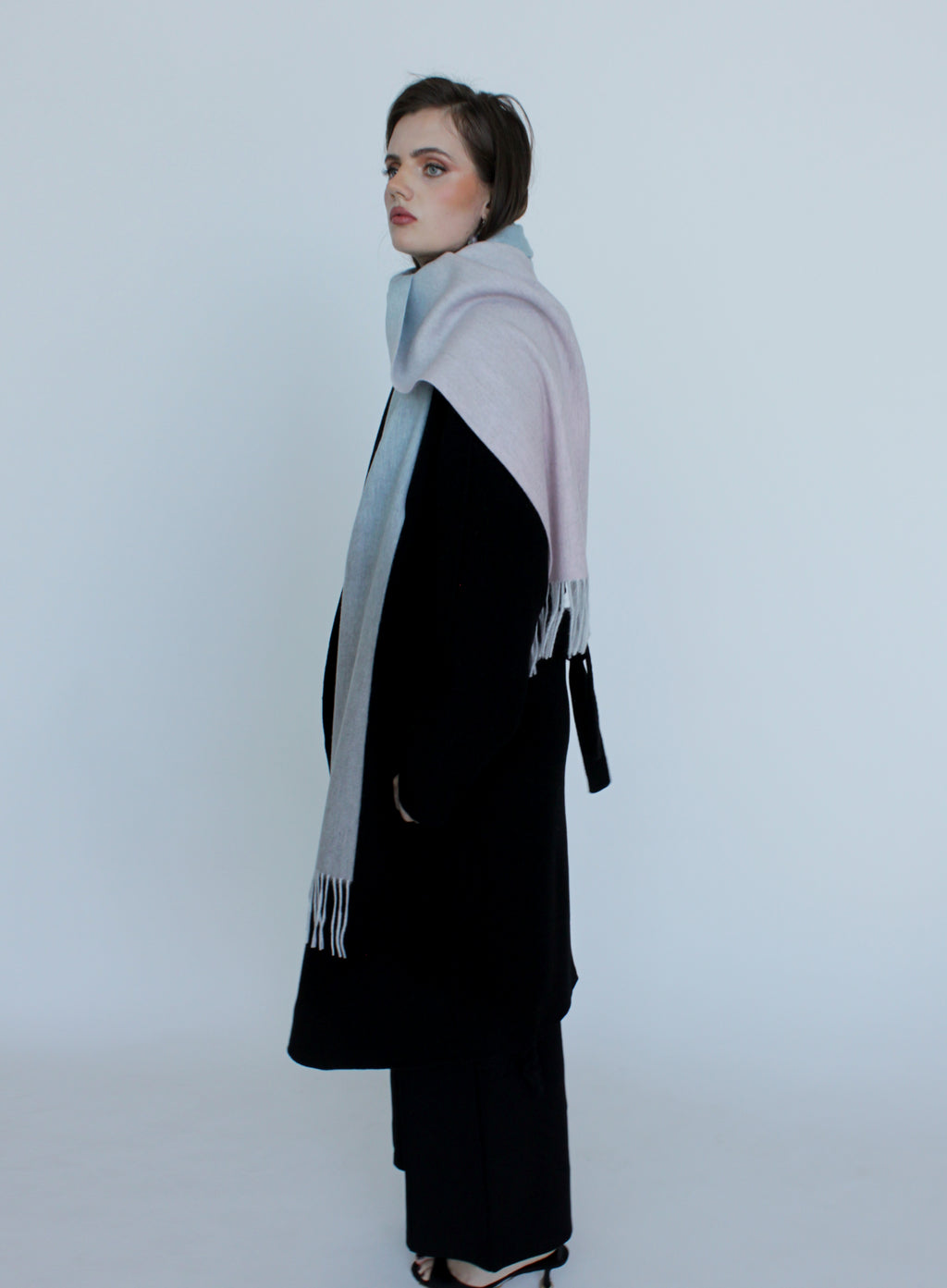 Woman wearing a black outfit with a large gray scarf on a white background