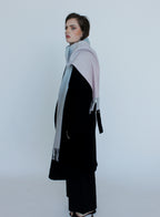 Woman wearing a black outfit with a large gray scarf on a white background