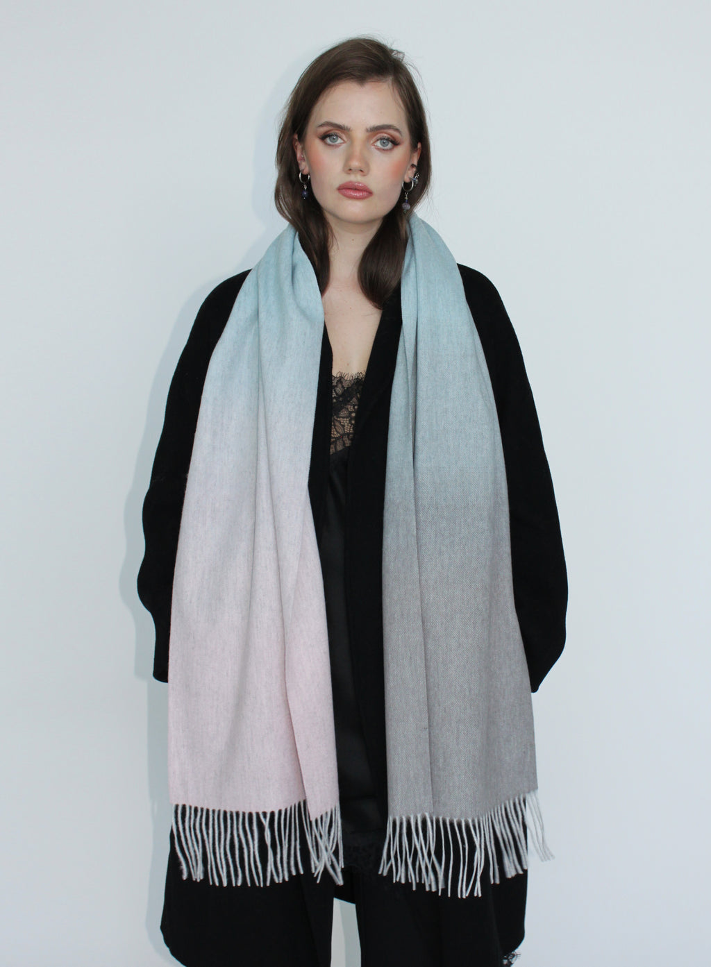 Woman wearing a gradient scarf with black, white, and gray colors on a plain background