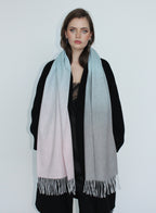 Woman wearing a gradient scarf with black, white, and gray colors on a plain background