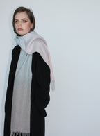 Woman wearing a light gray scarf with a black outfit against a white background