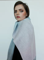 Woman wearing a light gray shawl against a white background