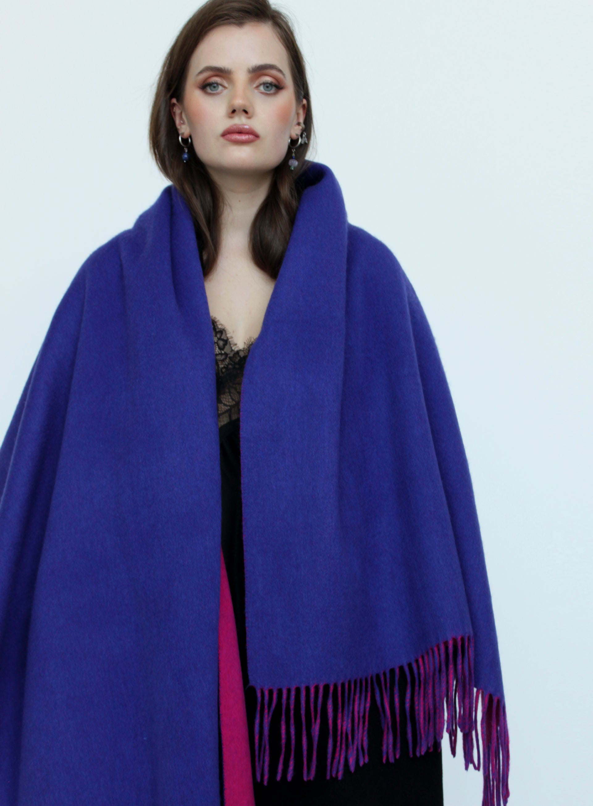 Woman wearing a blue scarf with purple fringe on a white background