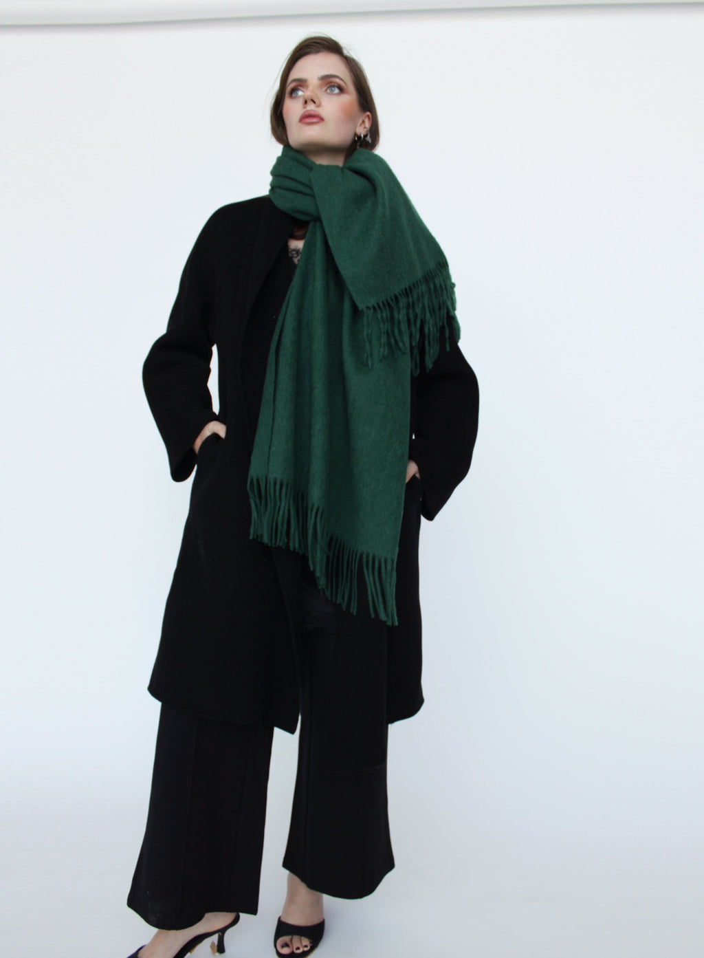 Person wearing a green scarf and black outfit against a white background