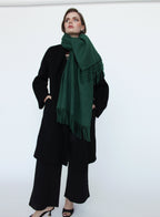 Person wearing a green scarf and black outfit against a white background