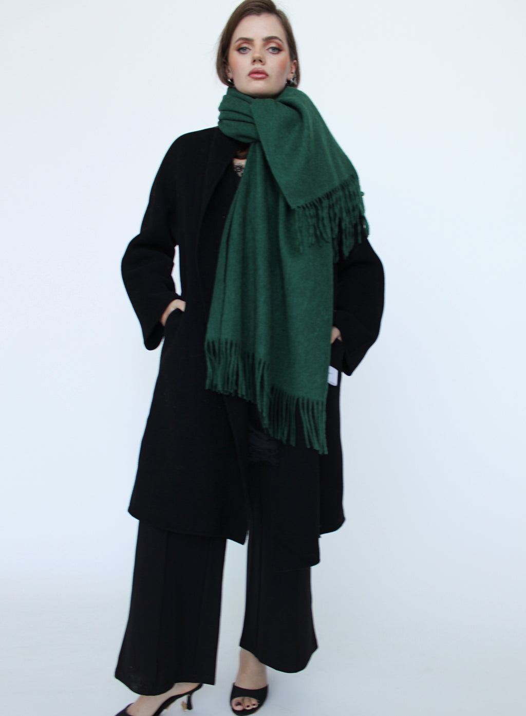 Person wearing a dark green scarf and black outfit on a white background