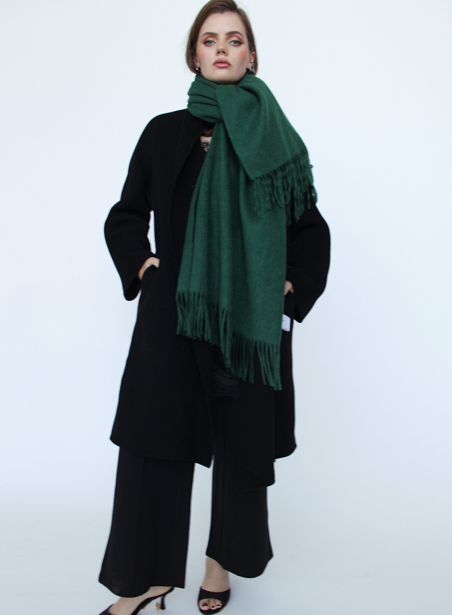 Person wearing a dark green scarf and black outfit on a white background