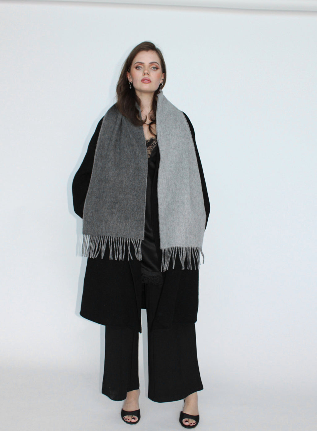 Woman wearing a gray scarf and black outfit on a white background
