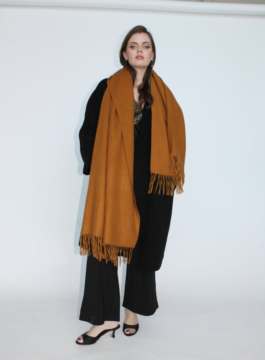 Woman wearing a mustard yellow scarf with black outfit on a white background