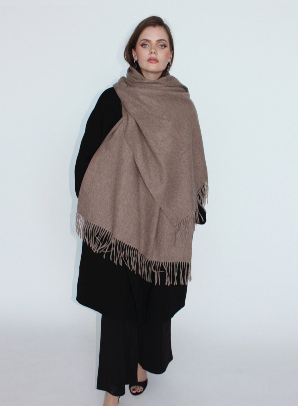 Woman wearing a large brown scarf on a white background