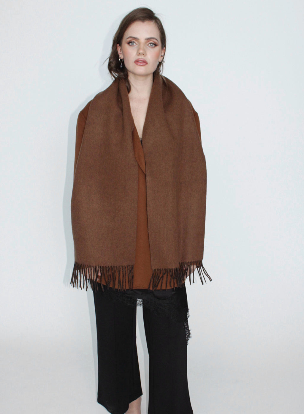Woman wearing a brown scarf with fringe on a white background