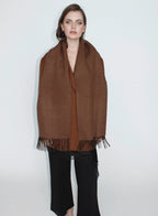 Woman wearing a brown scarf with fringe on a white background