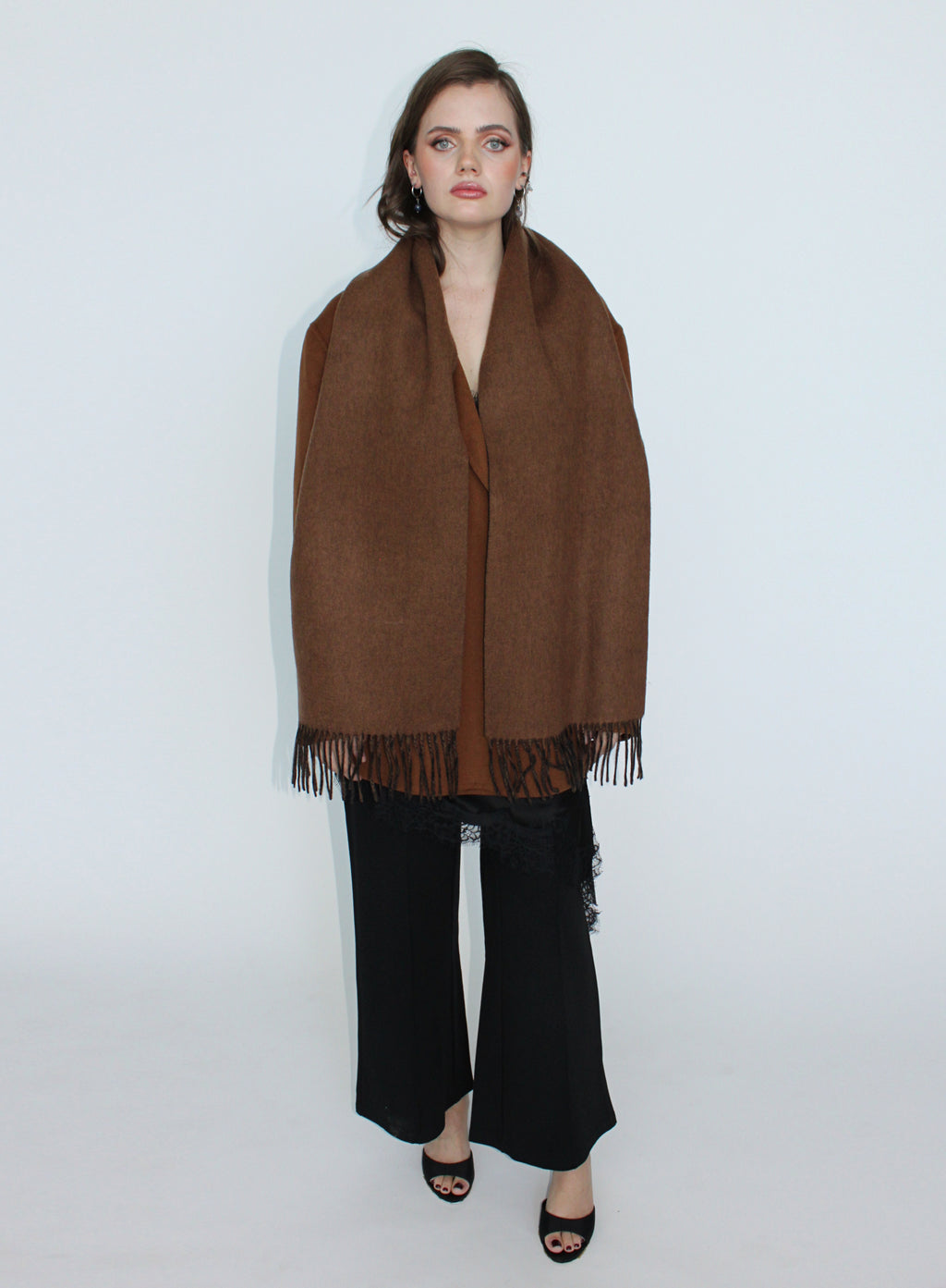 Woman wearing a brown scarf and black pants on a white background