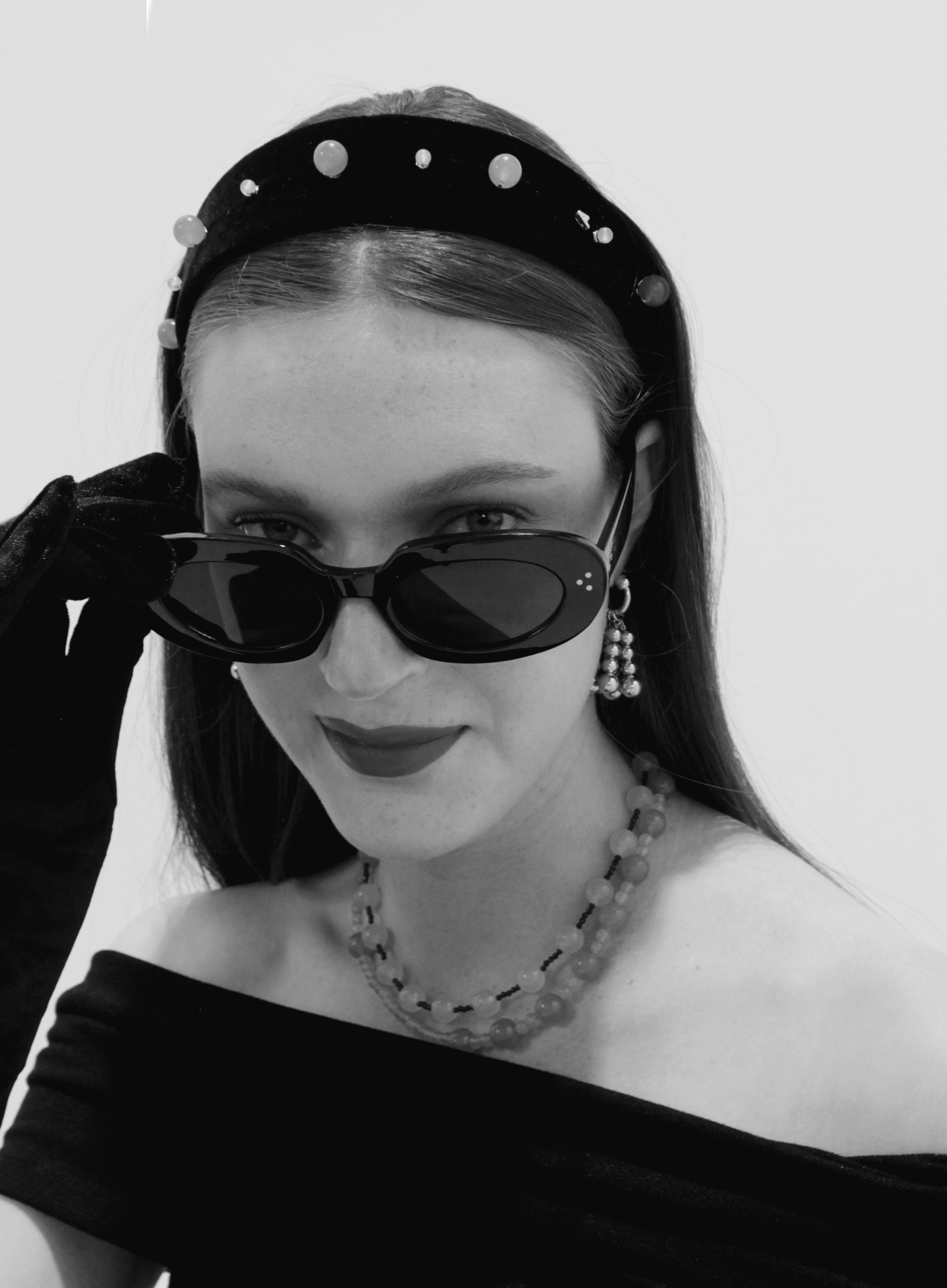 Black and white portrait of a woman wearing sunglasses and a decorative headband.