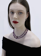 Woman wearing a purple beaded necklace against a white background