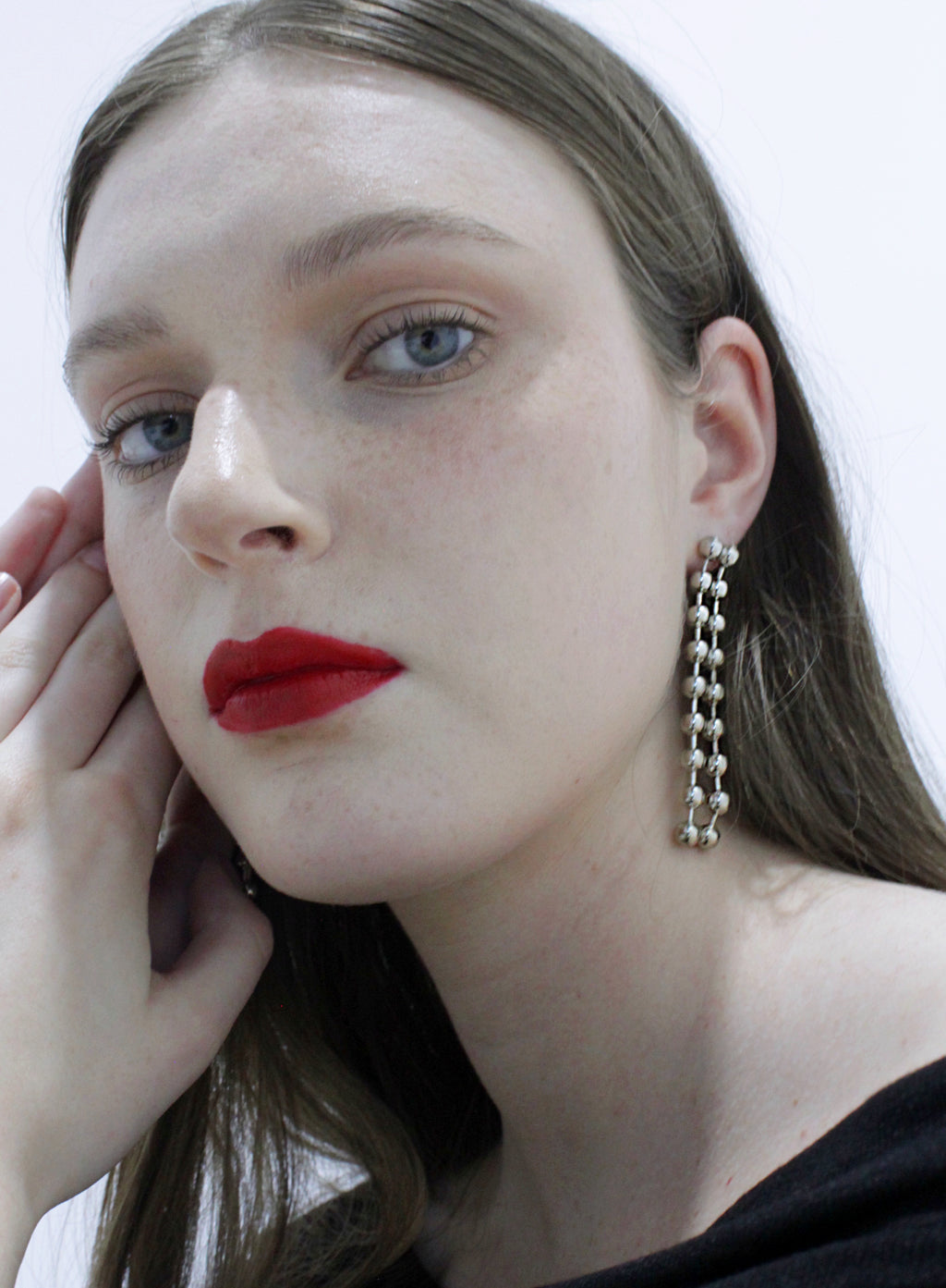 Close-up of a woman wearing a dangling earring with a plain background