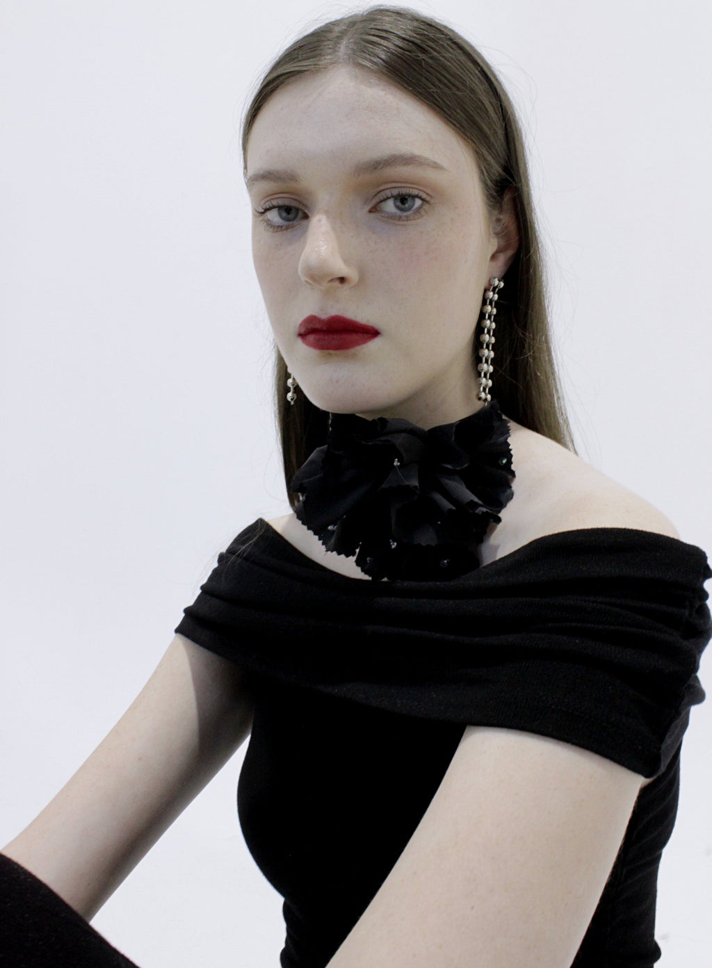 Woman wearing a black off-shoulder top with floral details on a white background