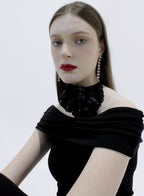 Woman wearing a black off-shoulder top with floral details on a white background