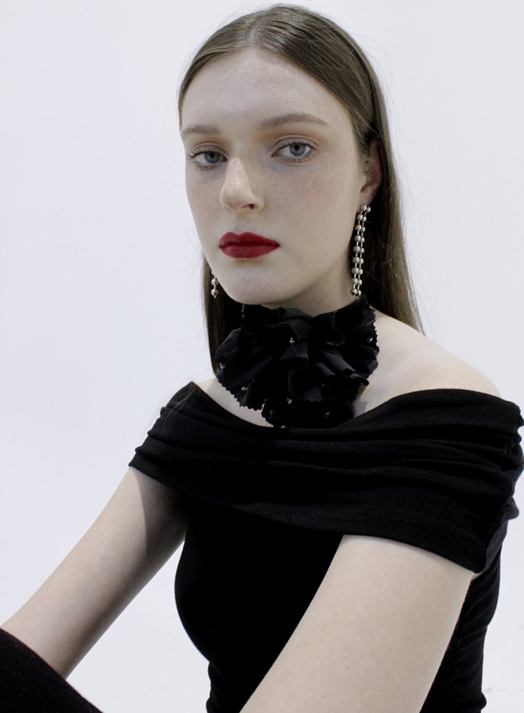 Woman wearing a black off-shoulder top with floral details on a white background