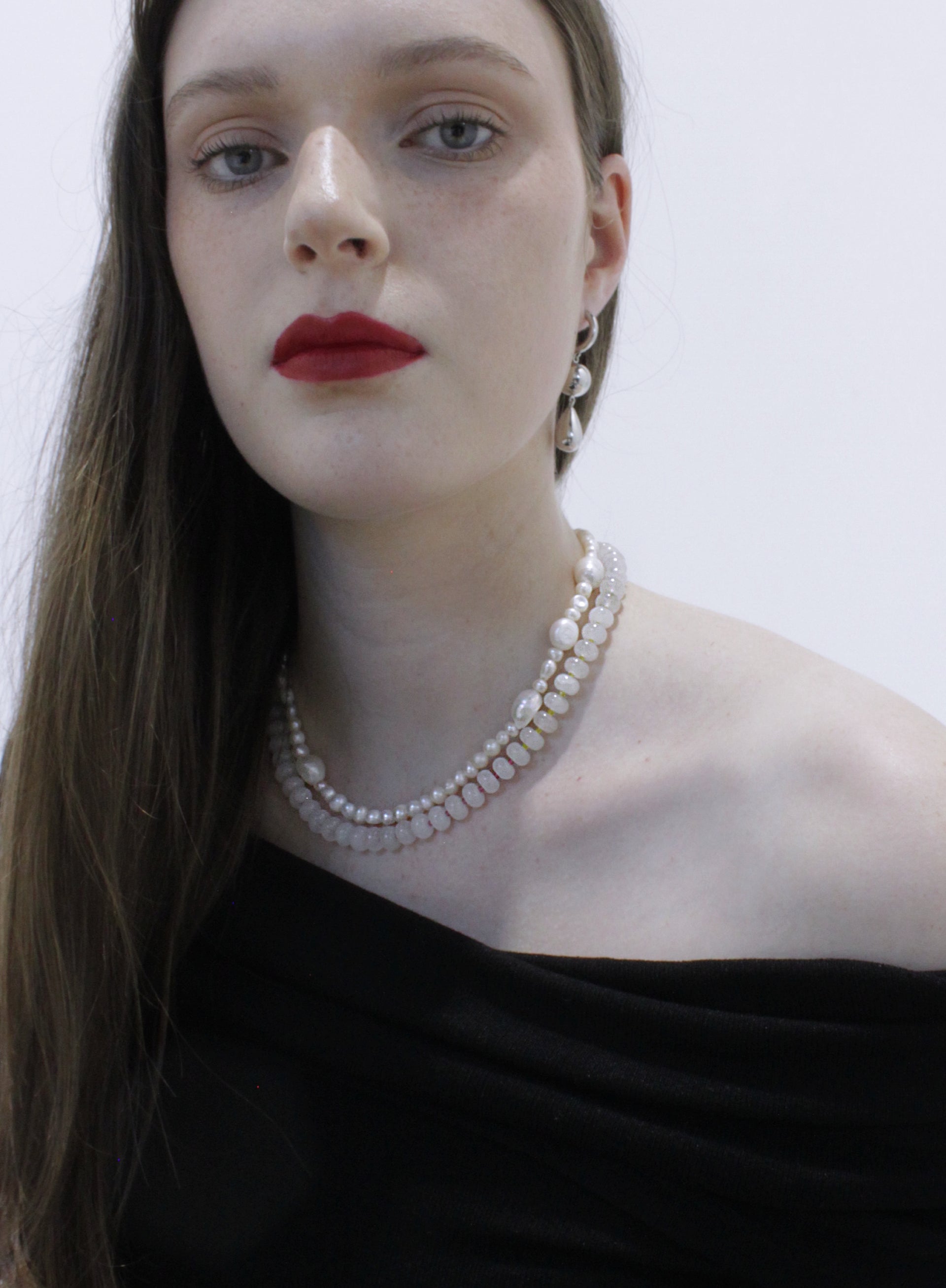 Woman wearing a pearl necklace against a plain background
