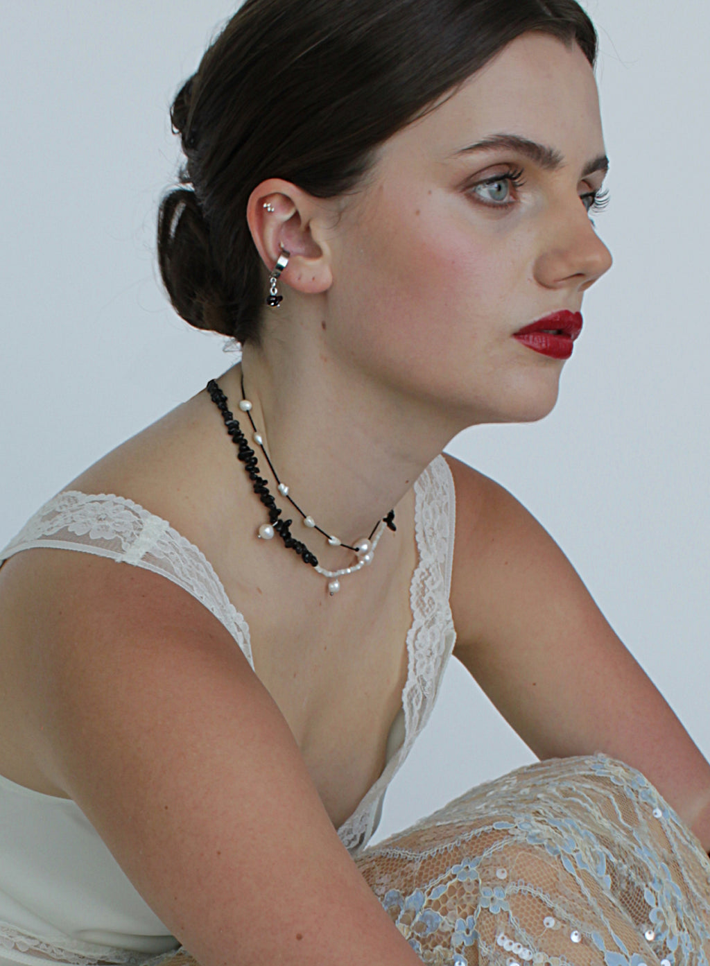 Woman wearing a earcuff and necklace with a white background