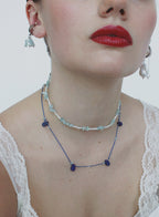 Close-up of a person wearing a beaded necklace with a plain background
