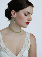 Woman wearing a green beaded necklace and earrings on a plain background