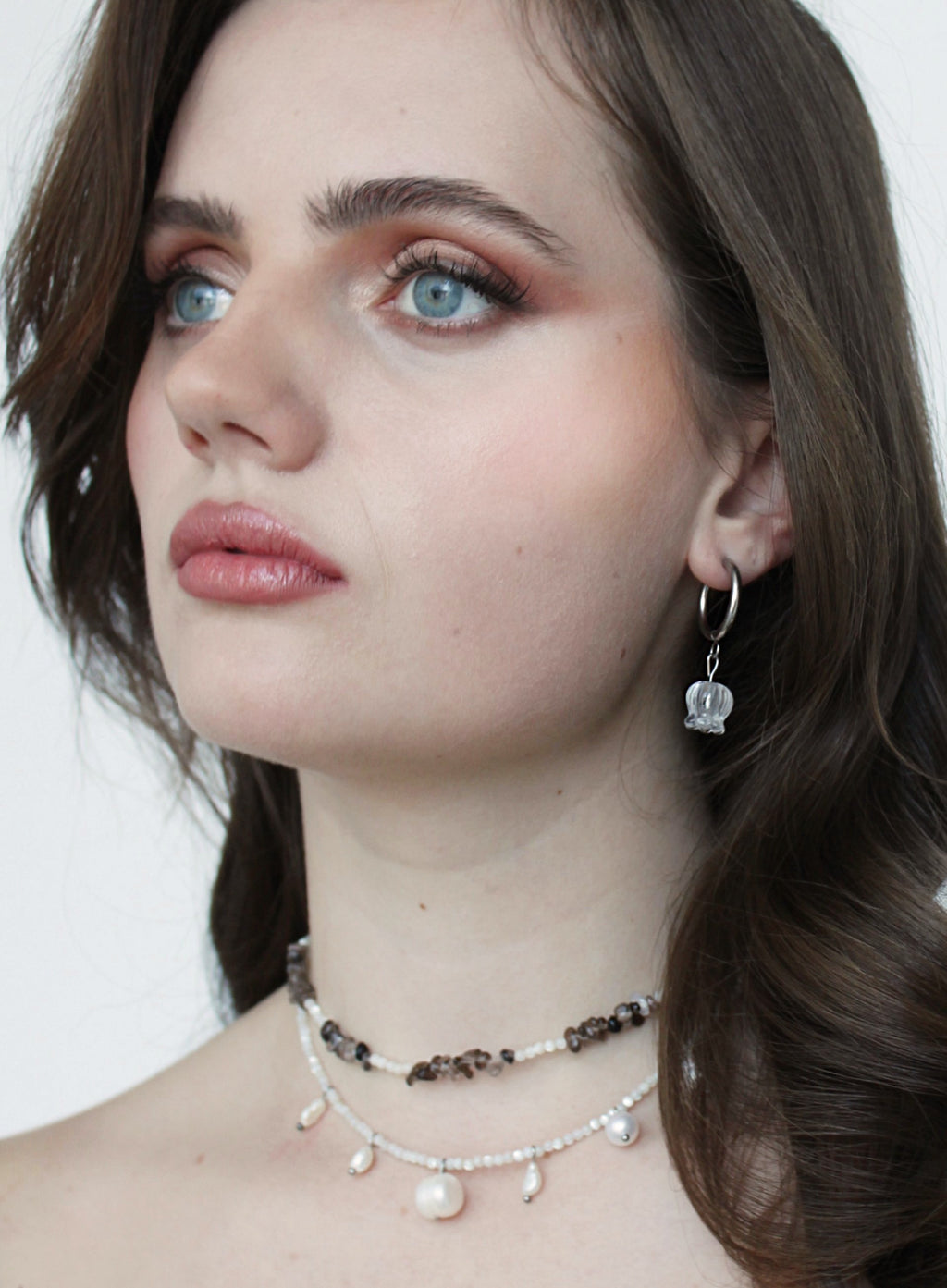 Close-up of a woman wearing jewelry with a plain background