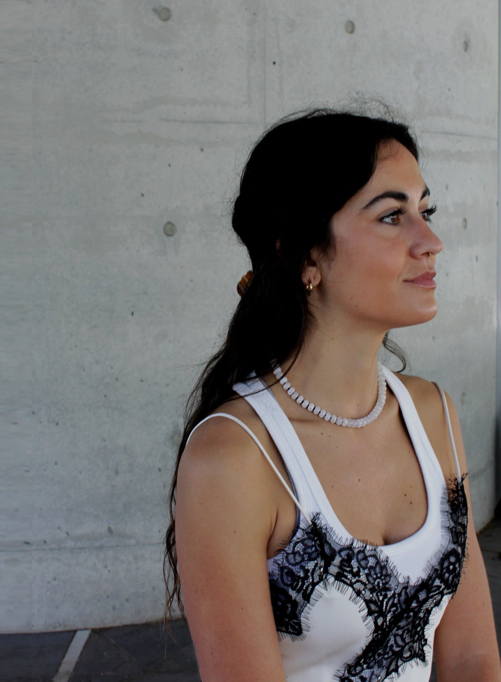 Woman wearing a white tank top with black lace with white jade necklace